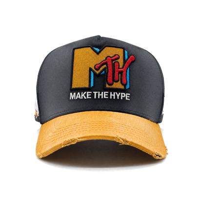 Front view of MAKE THE HYPE TV with a faded charcoal crown and warm golden-yellow brim with pale streaks following the cotton twill